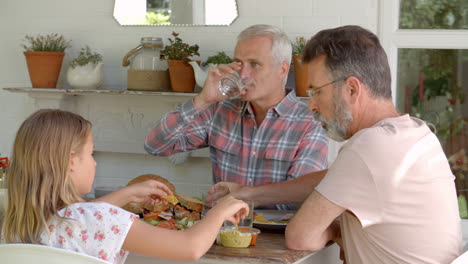 same sex family at home eating meal on outdoor verandah