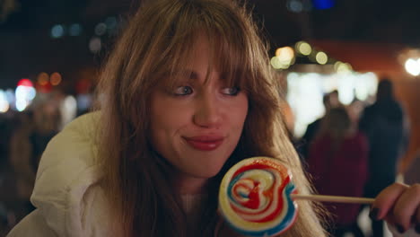 playful woman holding lollipop at christmas market with festive mood closeup.