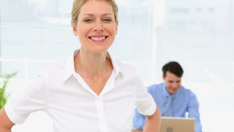 businesswoman smiling at camera with colleague behind her