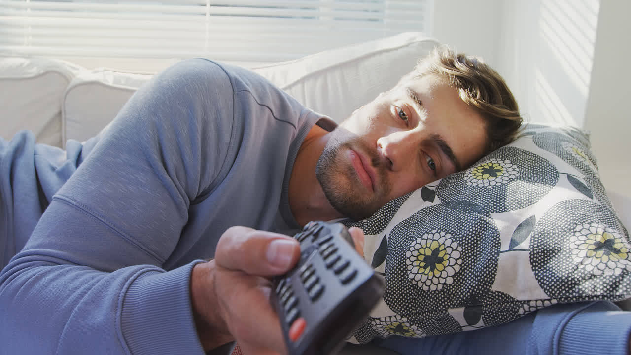 joven acostado en el sofá viendo televisión 4k 4k