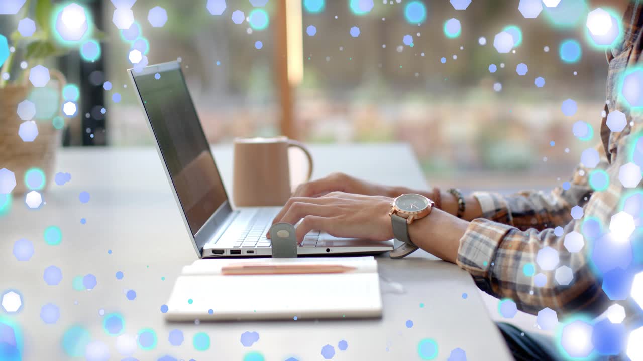 Man typing at laptop, keystrokes initiating blue bokeh overlay while working remotely for designers
