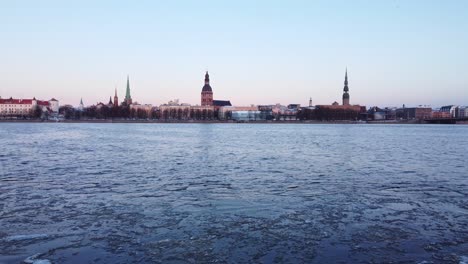 icy daugava river and towers of riga skyline, low altitude aerial view