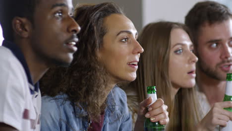 deux couples assis sur le canapé, mangeant des collations et célébrant la victoire de l'équipe en regardant la télévision