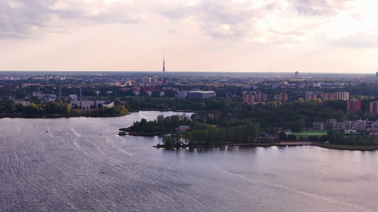 дронный снимок озера кизезерс с горизонтом риги, зелеными пространствами и закатным светом.