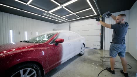 car washing cleaning with foam and high pressured water. red car