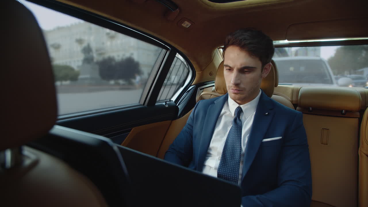 un profesional masculino serio trabajando con una computadora portátil en un coche de negocios.