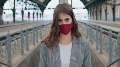 woman in a red face mask at a train station