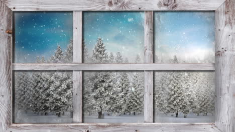wooden window frame against snow falling over multiple trees on winter landscape