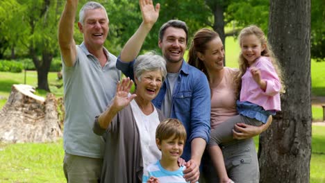 Multi-generation-family-posing-and-waving-at-camera-in-a-park