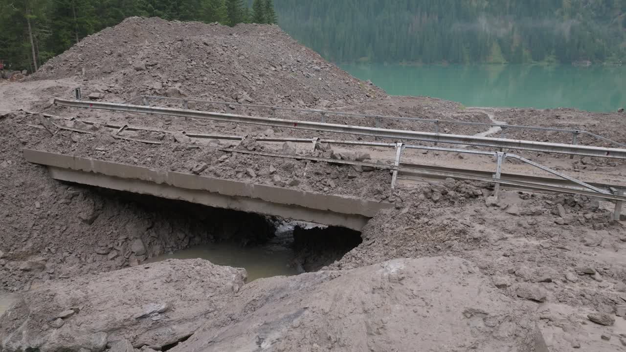 Heavy machinery toils in the muddy aftermath of a landslide, capturing the essence of nature's unpredictability and human resilience