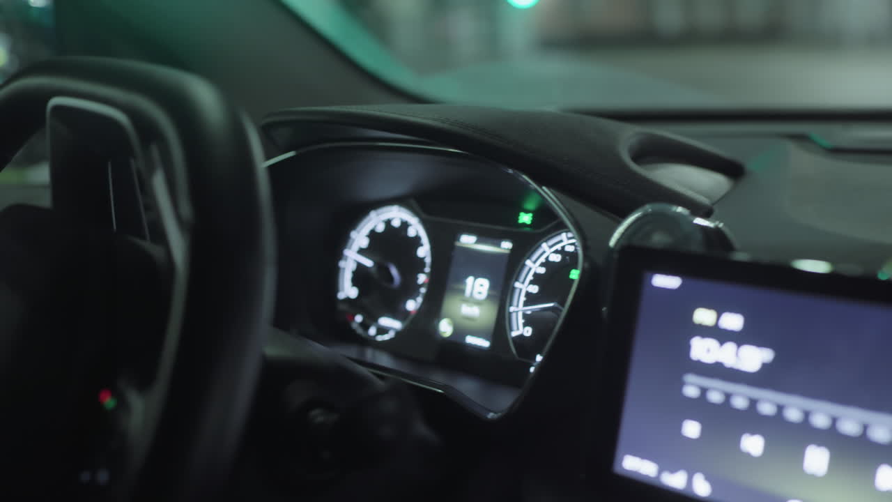 Close up of lady with polished nails driving at night, illuminated dashboard, glowing indicators visible, interior softly lit with ambient reflection from infotainment screen