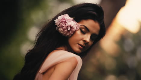 seductora mujer morena con una flor rosa en el cabello mirando a la cámara girando en una cautivadora sensación de intoxicación
