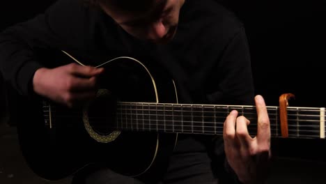 guitarist strumming a guitar with capo on