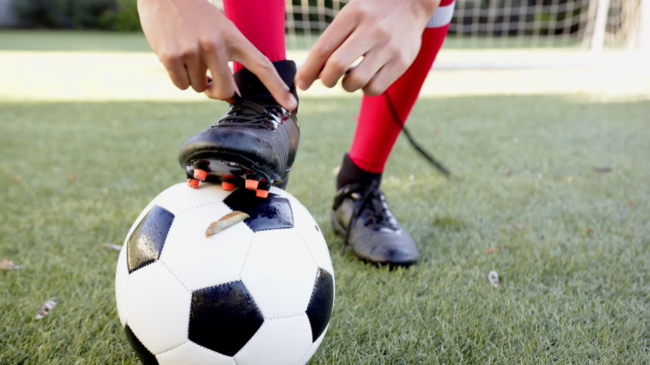 Giocatore che allaccia i lacci degli scarpini da calcio, preparandosi per la partita sul campo
