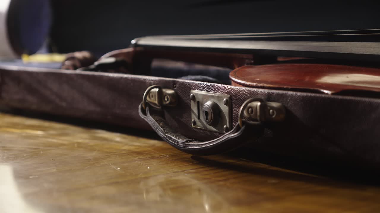 Musician removes antique violin from secure protective carry case