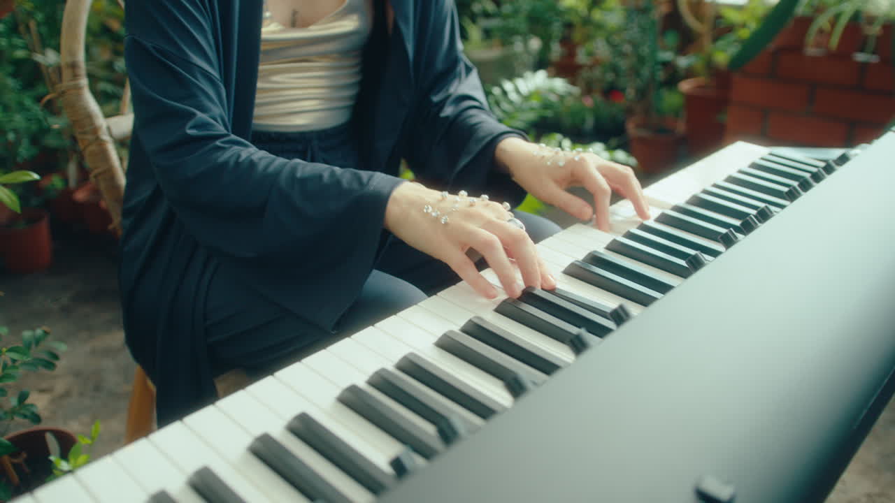 Woman with Crystal-Like Embellishments on Hands Playing Keyboard in Greenhouse