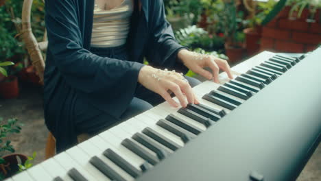 woman with crystal-like embellishments on hands playing keyboard in greenhouse