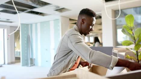 Casual-african-american-businessman-carrying-box-moving-into-office,-slow-motion-with-copy-space