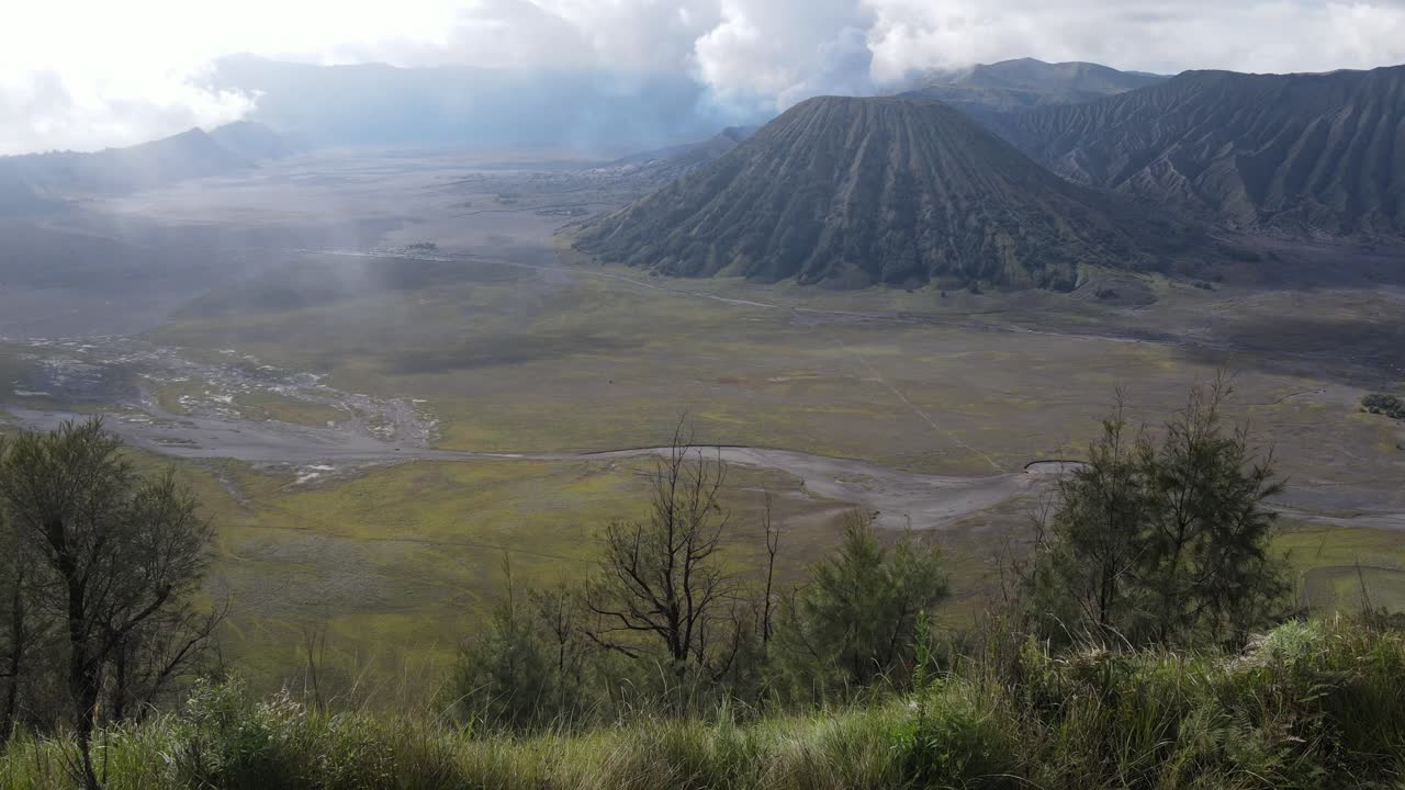 vista aérea, por la mañana, la hermosa zona del monte bromo está ligeramente humeante y la sabana es verde