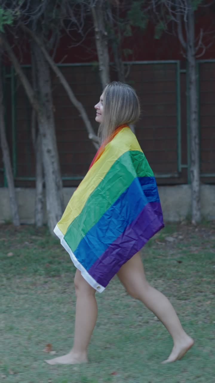 Woman wrapped in pride flag walking outside