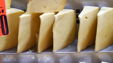 close-up of stacked wedges of yellow cheese on display at a market