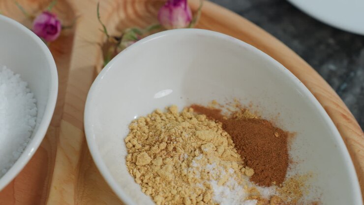 Close-up of a white cup filled with sugar alongside powder beverage and delicate dry flowers on a wooden tray, warm lighting enhances textures, creating a cozy and rustic kitchen ambiance