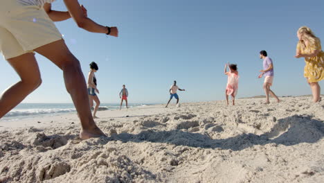 Diversos-Amigos-Jugando-Un-Partido-De-Fútbol-En-Una-Playa-De-Arena,-Con-Espacio-Para-Copiar