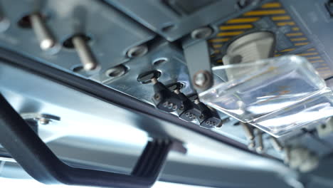 close up pilot operating switches on the overhead panel in the cockpit