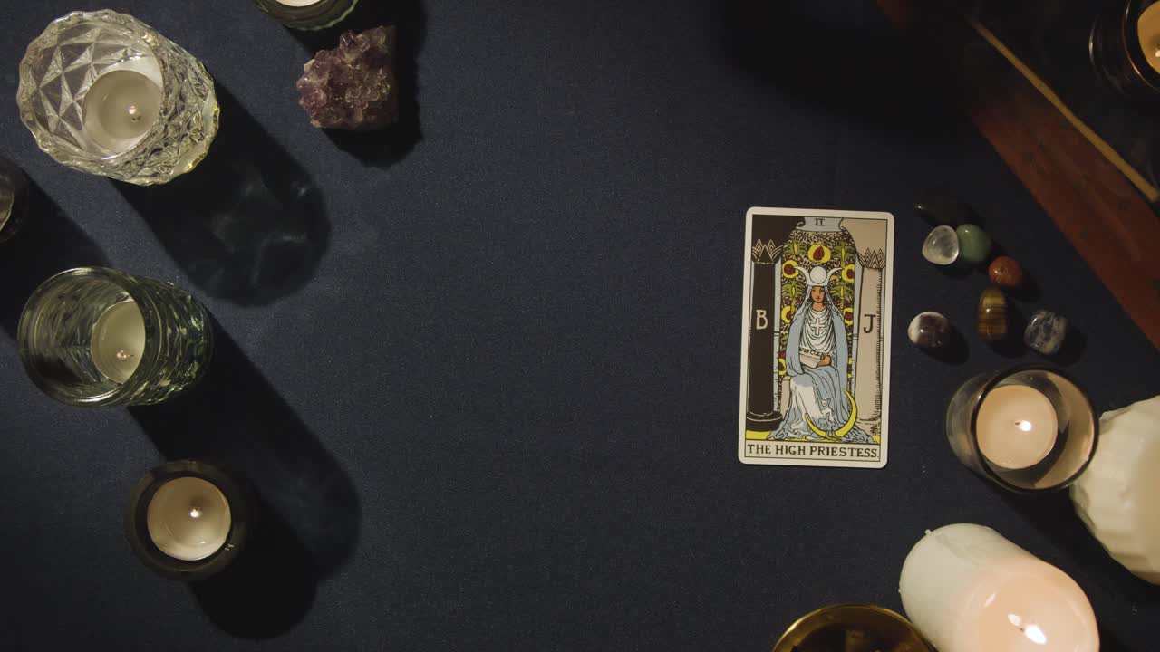 toma aérea de una persona que da una lectura de cartas del tarot colocando la carta de la alta sacerdotisa en la mesa 1