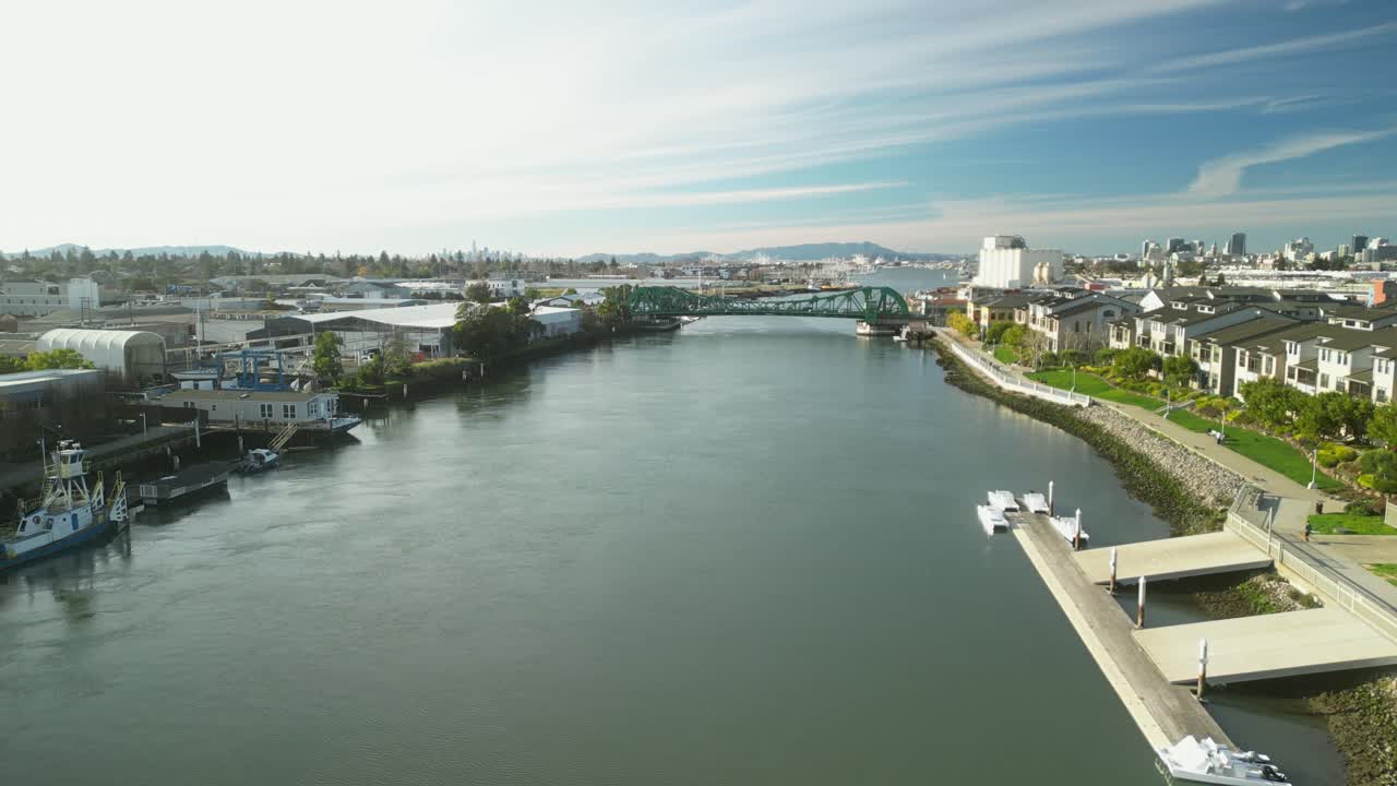 An aerial drone view captures the Tidal Canal and Park Street Bridge in Alameda, showcasing calm waters and urban charm.
