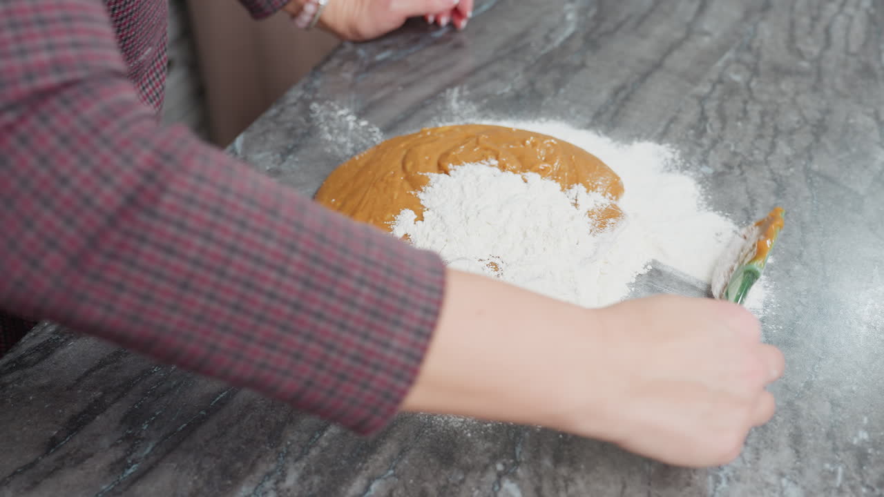 깨한 카운터에 두꺼운 갈색 반죽을 밀가루로 기 위해 녹색 스파라를 사용하는 여성의 공중 사진, 편안한 부에서 베이킹 준비, 손에 초점을 맞추고