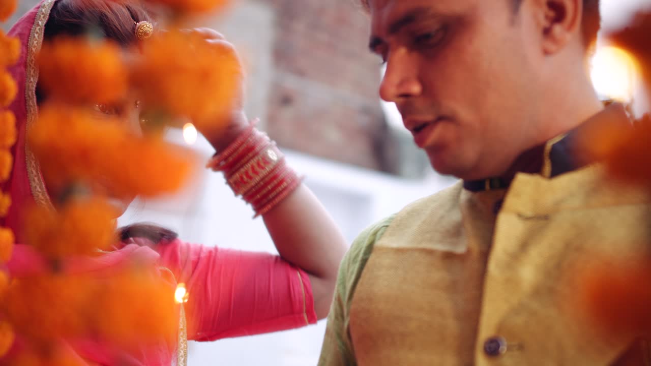 Couple celebrate a colorful Diwali rangoli- red pink orange green