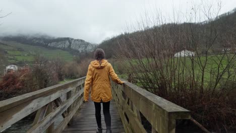 hiker in yellow jacket on a foggy countryside bridge and walk on a misty mountain