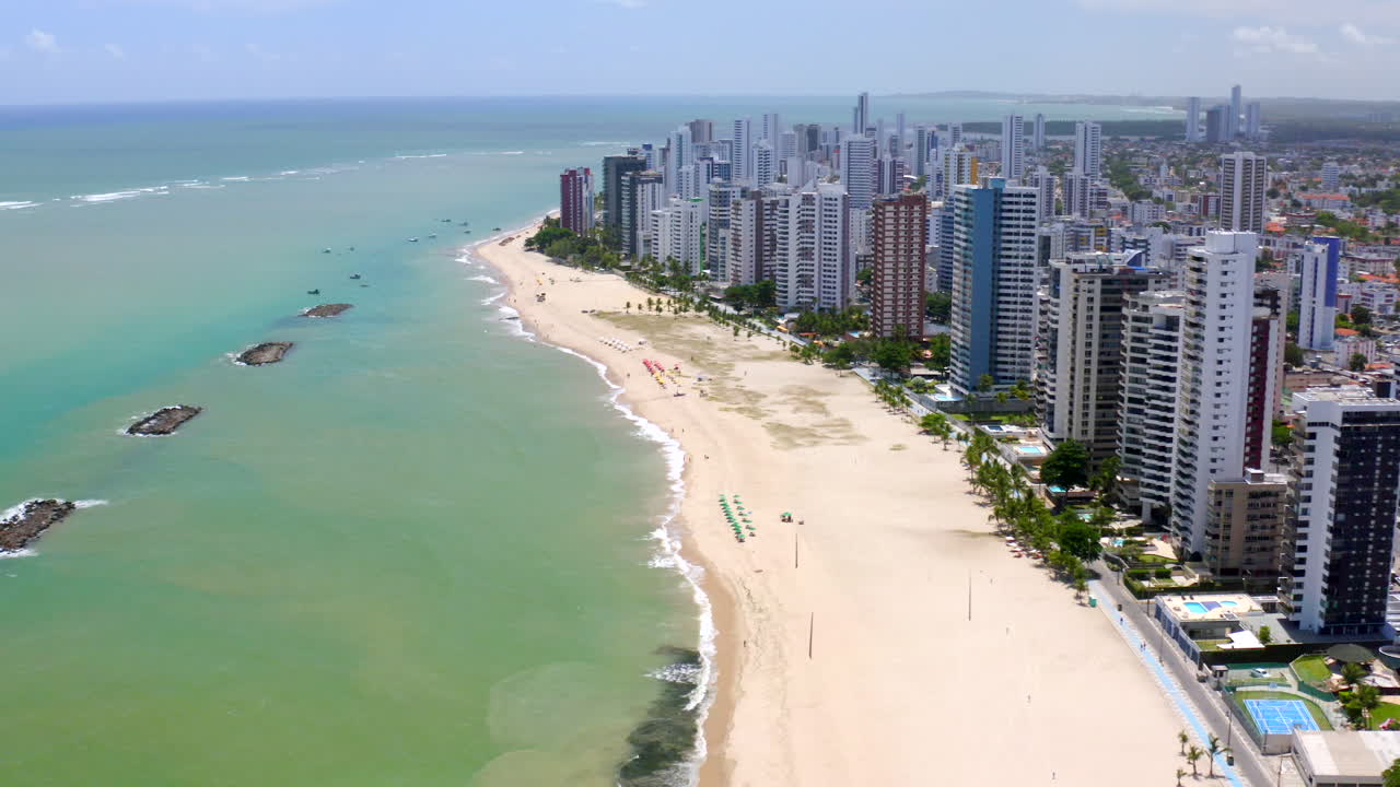 Coastal aerial of Jaboatão dos Guararapes Pernambuco Northeast Brazil displaying the beautiful sea sandy beach clear blue sky city skyline perfect summer vacation image with boat and beach umbrella