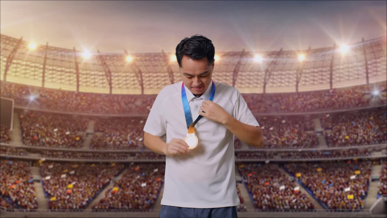 금메달을 입고 카메라를 향해 미소 짓는 아시아 남자가 경기장에서 첫 우승자로 자랑스럽게 승리합니다.