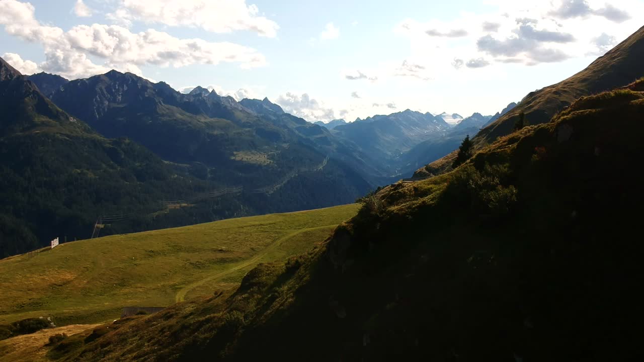Lenta carrellata aerea sopra un ruscello alpino roccioso con acqua glaciale che si infrange su rocce di colore chiaro e fortemente erose.