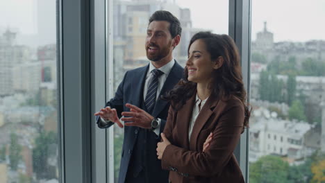 Friendly-manager-speaking-woman-colleague-at-office-corridor-closeup.-Work-break