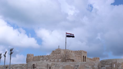 Egyptian-flag-waving-at-Citadel-Qaitbay-fort-castle-on-sunny-day