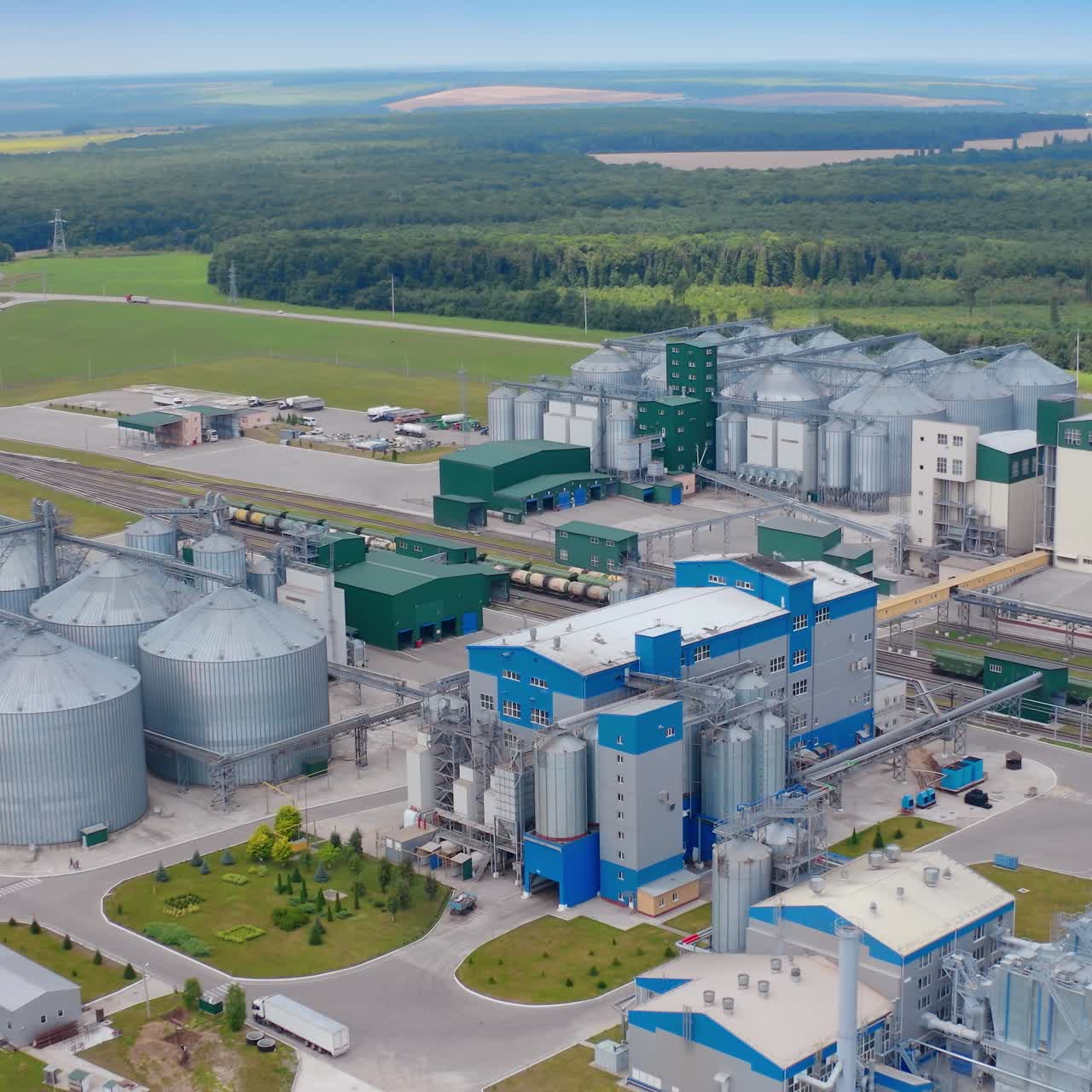 Modern industry surrounded by nature. Grain elevators on large agriculture factory on field. Grain-drying complex in rural land. Aerial view