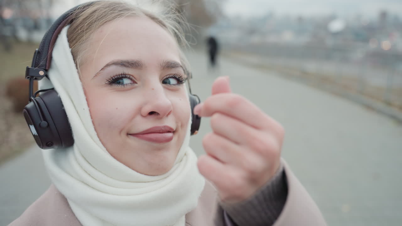 Donna in clima freddo che vive momenti pacifici e riflessivi durante una passeggiata. Scena deliziosa di una donna che passeggia tranquillamente lungo un silenzioso sentiero invernale ascoltando musica.