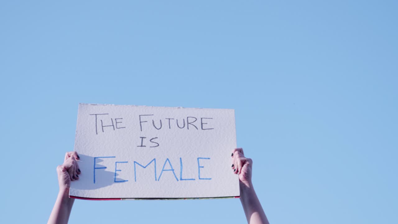 Hands Holding 'The Future Is Female' Protest Sign Against Blue Sky