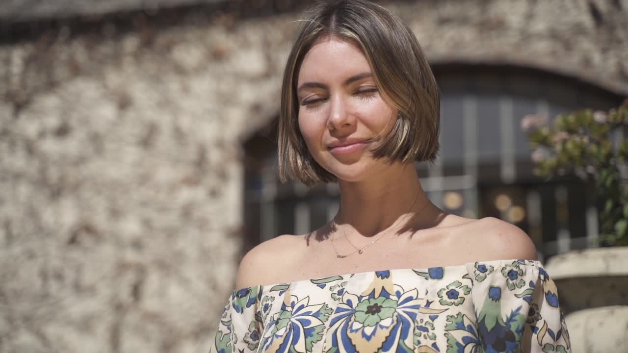 Giovane donna graziosa con i capelli corti sorride alla telecamera, al rallentatore