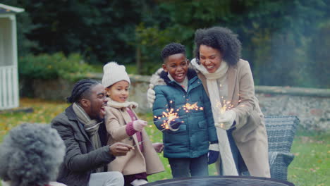 family having fun with sparklers in autumn garden at home - shot in slow motion