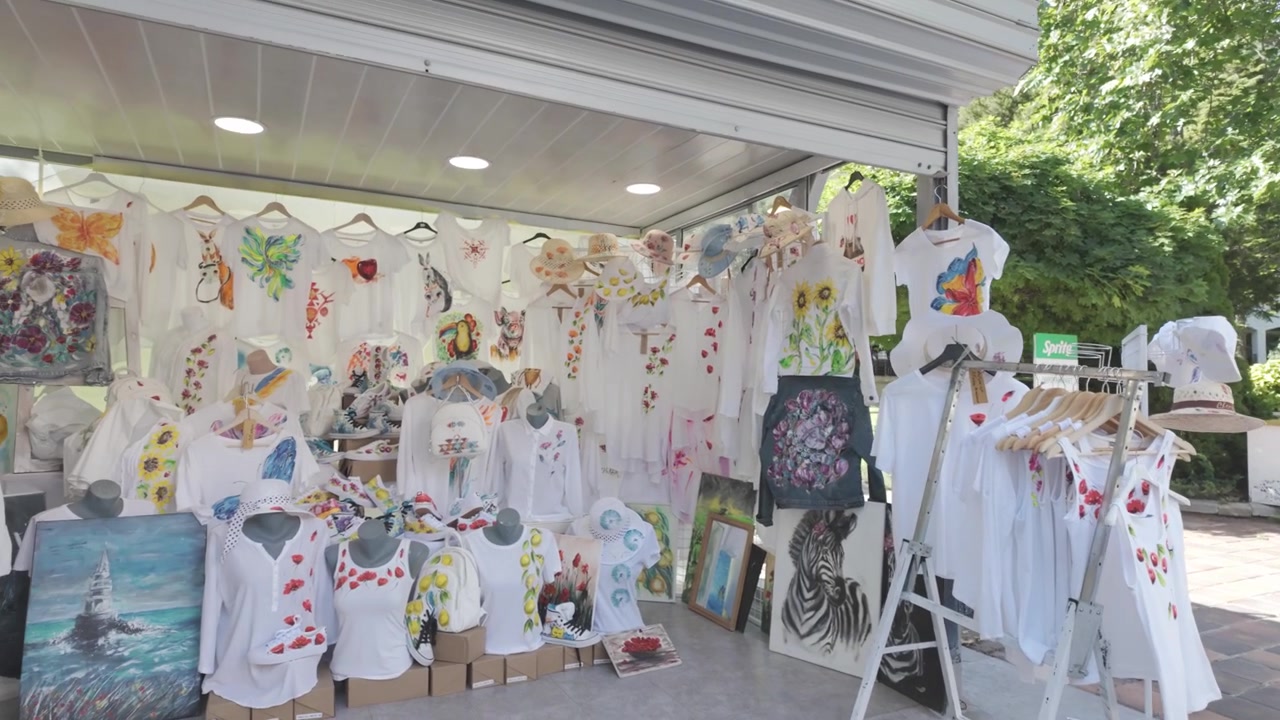 ブルガリア、アルベナで手描きの服とTシャツを販売する市場の屋台の4Kビデオ映像。