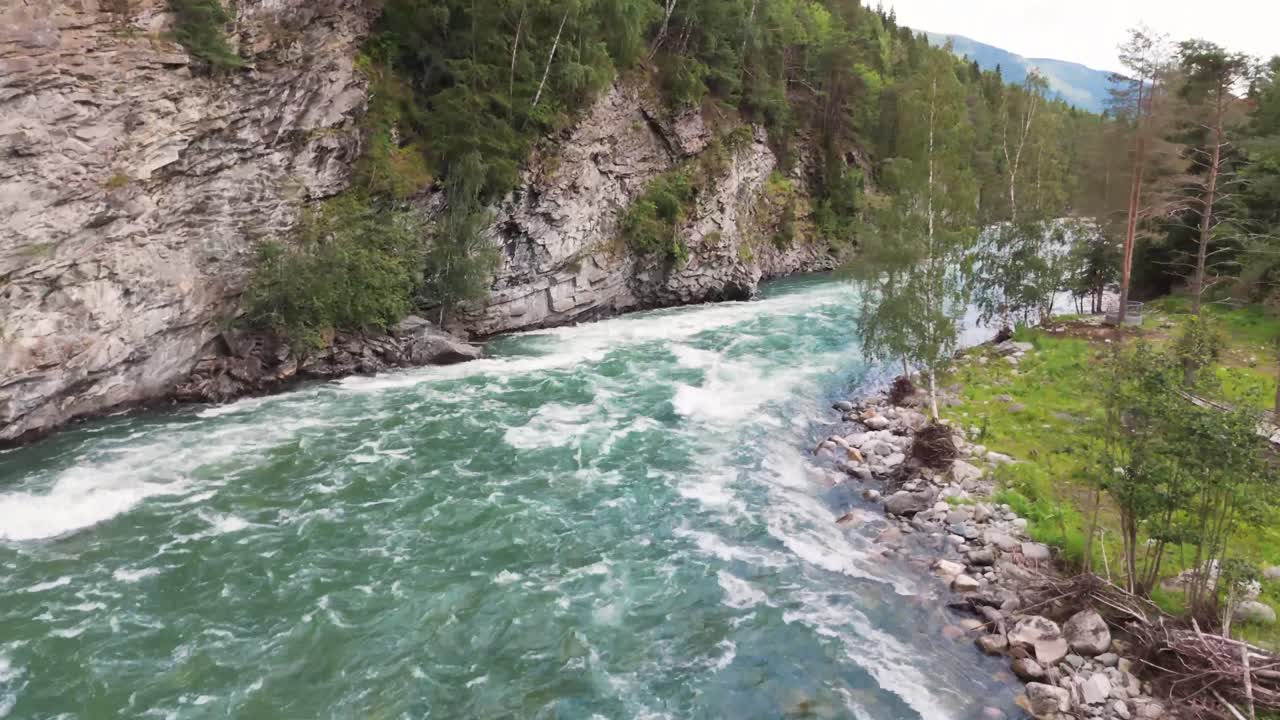 Aerial view of a fast flowing river cutting through a rocky gorge surrounded by lush trees and natural greenery