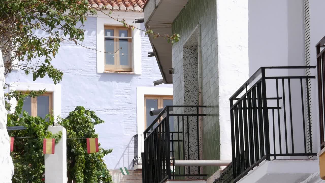 Tradisjonell arkitektur i Molvízar, Granada, med hvite og lyseblå fasader, smijerns balkonger og dekorative flagg