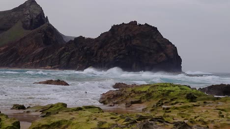 Corrientes-De-Olas-Turbulentas-Y-Agitadas-En-Una-Playa-De-Arena-Con-Rocas-De-Agua-De-Mar-Con-Un-Islote-Al-Fondo,-Isla-De-Porto-Santo-A-50-Fps