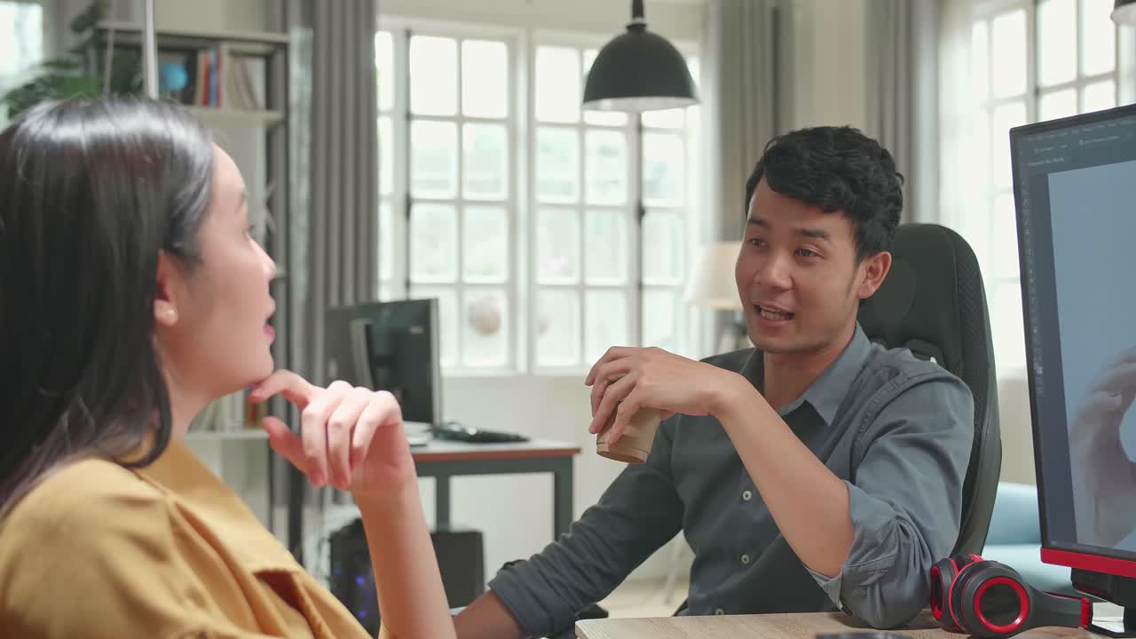 Happy Asian Male And Female Professional Editors Talking While Working In Photo Editing App / Software On A Personal Computer. Photo Editors Retouching Photos Of A Beautiful Girl