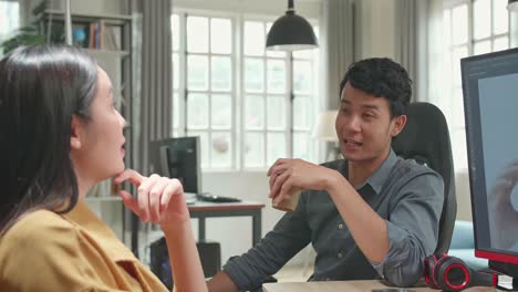 happy asian male and female professional editors talking while working in photo editing app / software on a personal computer. photo editors retouching photos of a beautiful girl