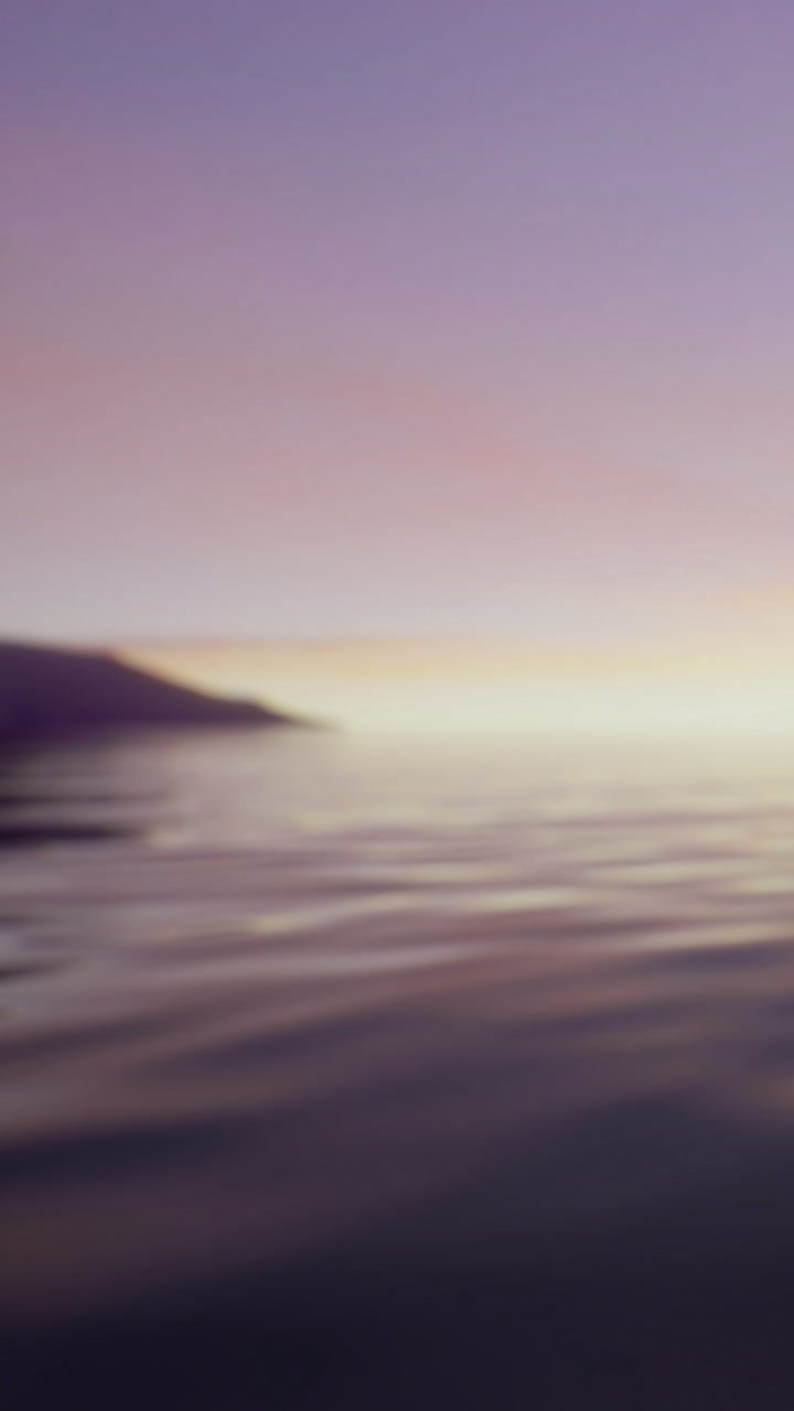 Sunset over calm waters with distant mountain in background and fading light